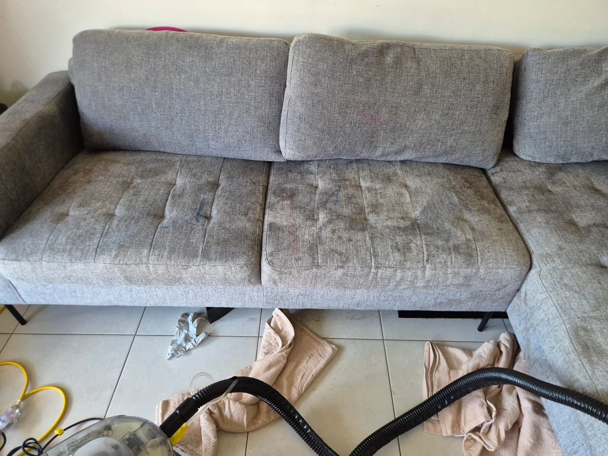 Four-seat grey couch before professional upholstery cleaning