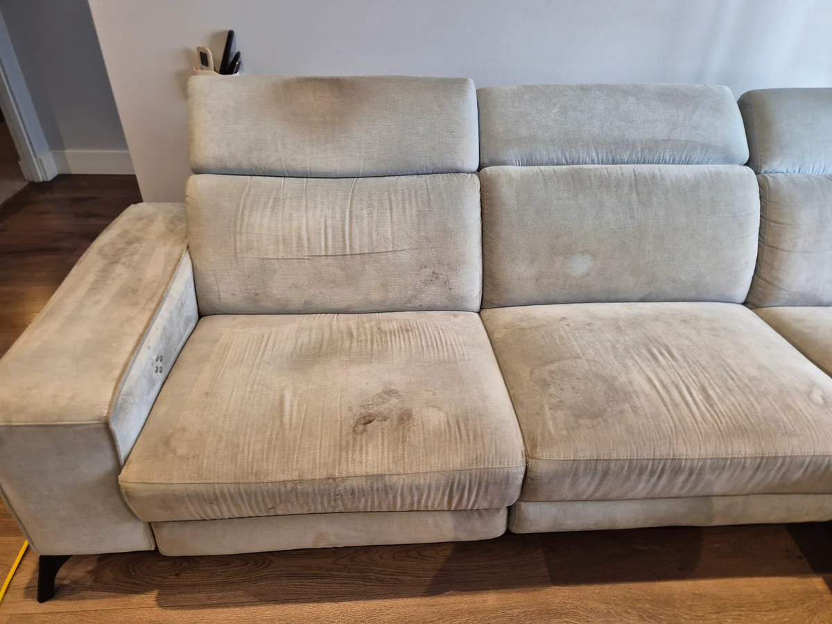 Light-fabric sofa with visible marks on its seats and armrest before cleaning